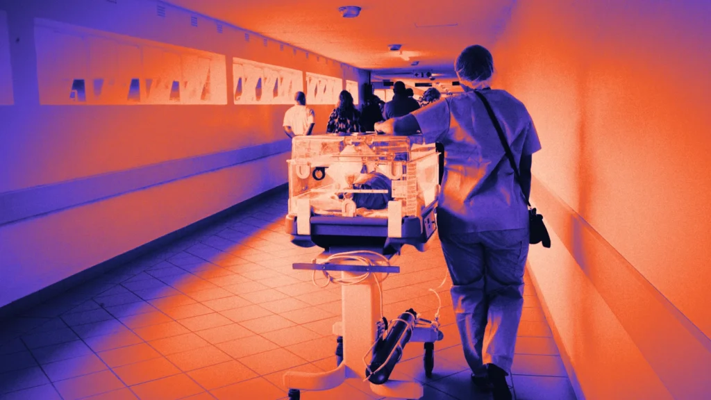 A nurse wheeling an incubator down a hospital corridor, in Arcsen colours
