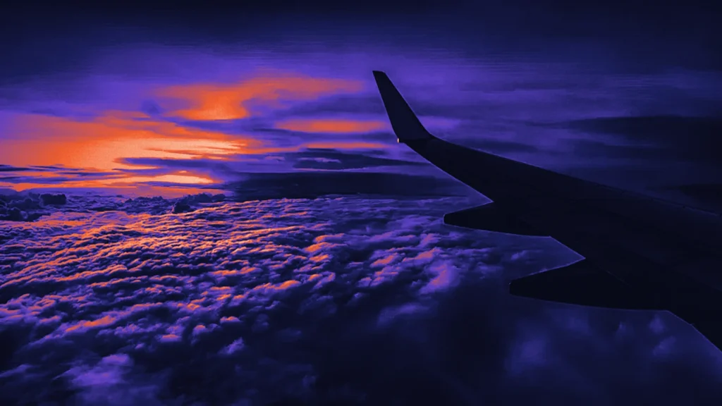 An aircraft wing above clouds at sunset, in Arcsen colours
